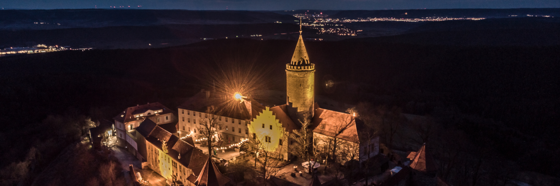 Luftaufnahme der Leuchtenburg bei Nacht mit Jena am Horizont © Stiftung Leuchtenburg, Foto: Daniel Suppe