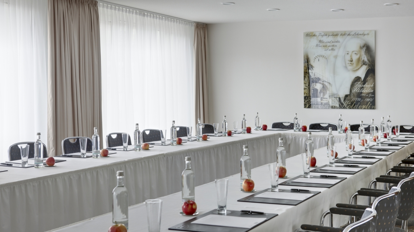 Steigenberger Esplanade Hotel Jena, Salon Hölderlin © Deutsche Hospitality, Foto: unbekannt Raum in U-Bestuhlung mit Schreibutensilien, Getränken und einem Portrait von Hölderlin im Hintergrund © Deutsche Hospitality, Foto: unbekannt