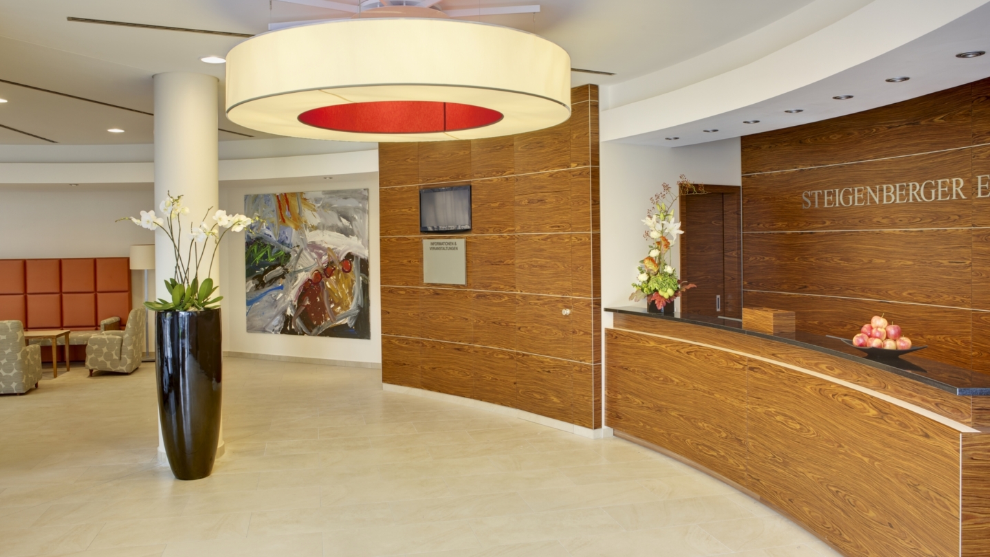 Steigenberger Esplanade Hotel Jena, Rezeption © Deutsche Hospitality, Foto: unbekannt Hotelrezeption im Steigenberger Esplanade Jena mit Sitzecke, Blumenvasen und Gemälde an der Wand © Deutsche Hospitality, Foto: unbekannt
