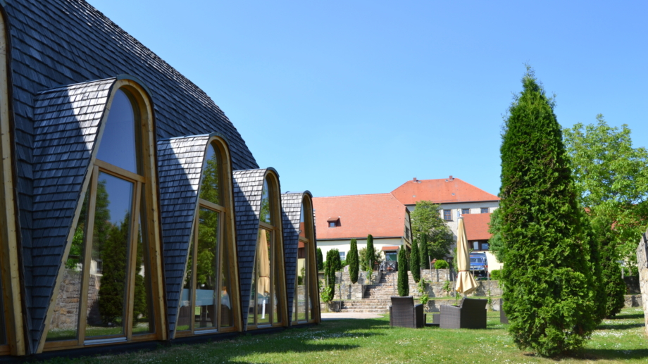 © Landratsamt Weimarer Land, Foto: Katy Kasten-Wutzler Weltdorfgemeinschaftshaus Maloca im Garten mit Sitzecken und Blick zum Schloss Auerstedt © Landratsamt Weimarer Land, Foto: Katy Kasten-Wutzler