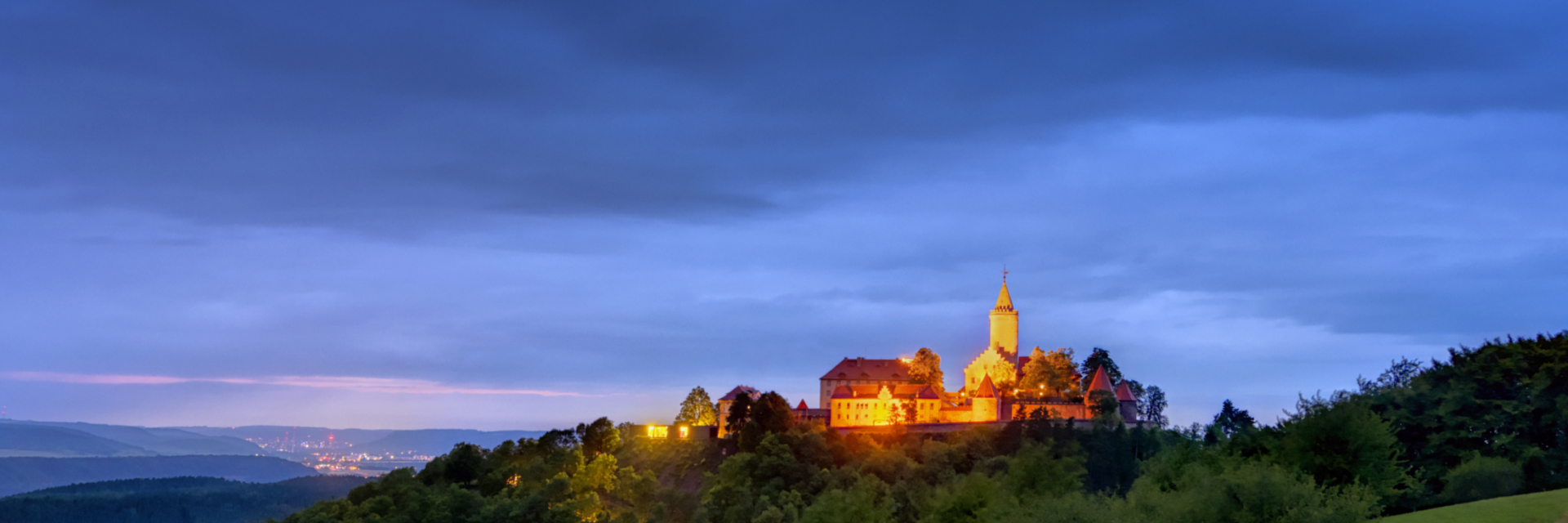 Blick auf die Leuchtenburg während der Dämmerung mit Jena im Hintergrund