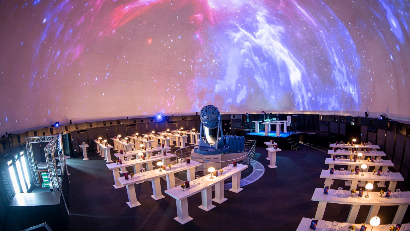 Der Kuppelsaal im Planetarium Jena beim Aufbau für den Digital-Gipfel 2023 mit Blick zur Bühne und zur Projektion eines astronomischen Himmels
